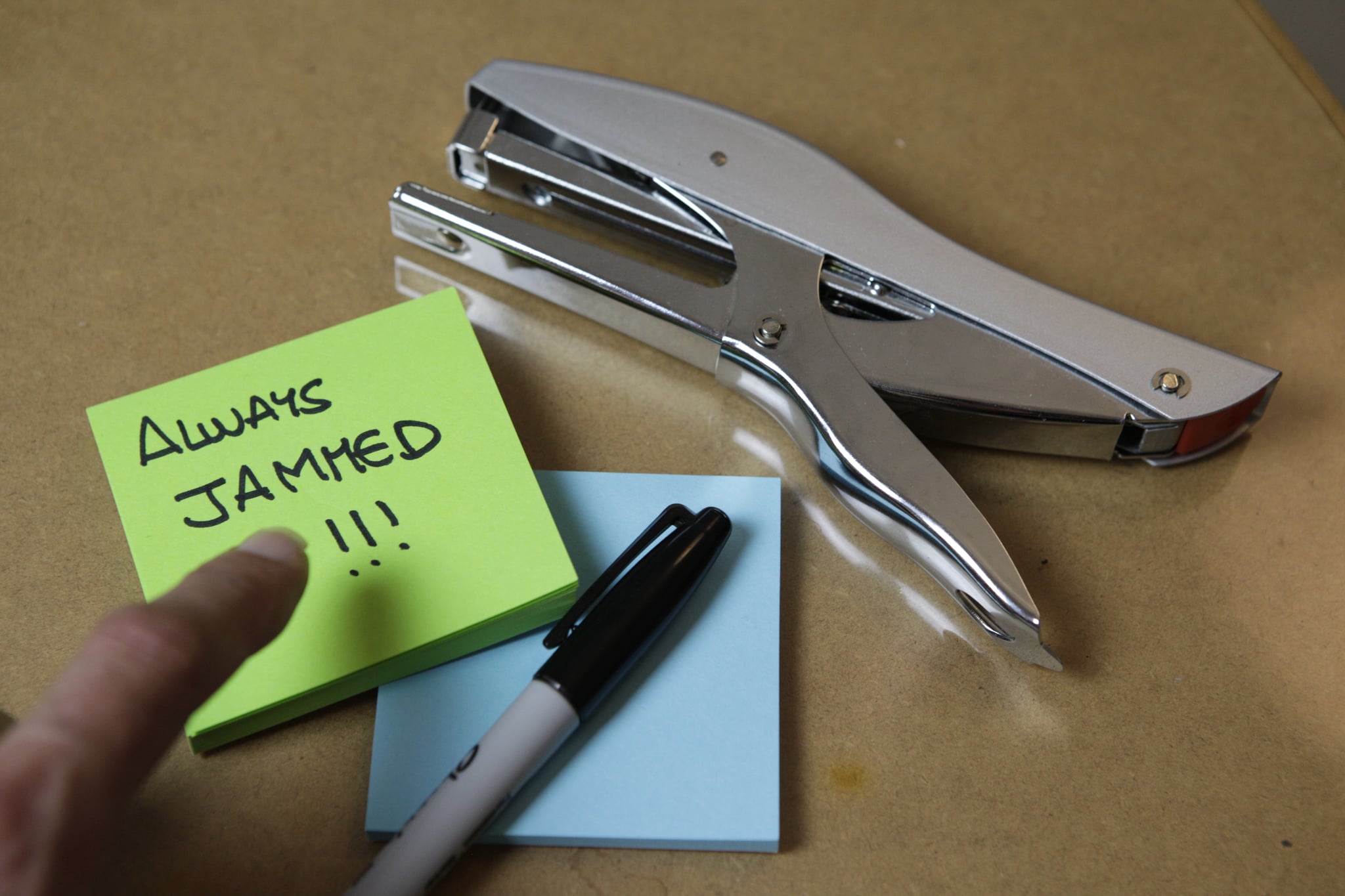 A metal stapler labelled “Always jammed!!!”, turning a familiar frustration into a visible shared signal.