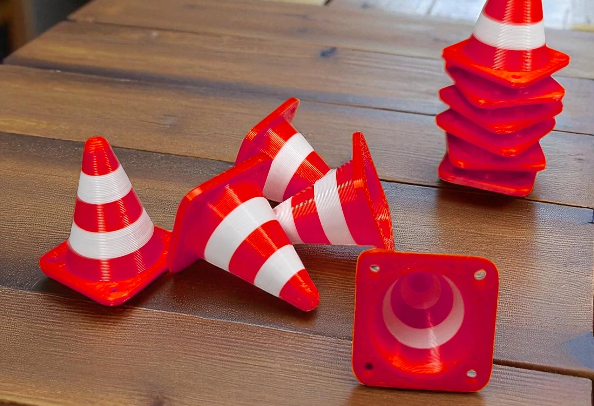 Small red and white traffic cones arranged on a wooden table.